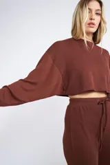 Buzo corto de tejido rib en color verde militar, con mangas largas y cuello redondo. Presenta un diseño holgado y cropped.