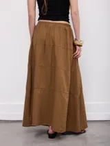 Falda larga marrón, de corte evasé con detalles de costuras horizontales y diseño fluido.