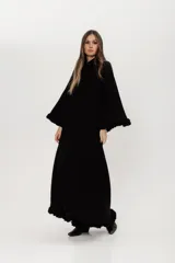 Vestido largo negro de punto con lanilla tipo canelón, corte trapecio y mangas largas.