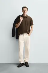 Polo de corte regular fit en tejido de algodón con estructura vertical color beige. Presenta cuello solapa, cierre frontal de botonadura y manga corta con rib.