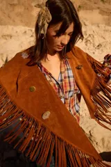 Chall de gamuza natural con diseño de flecos largos en todo el borde y detalle de pins metálicos decorativos en la parte frontal.