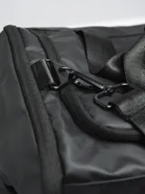 Bolso de viaje color gris oscuro, con múltiples compartimentos exteriores con cierre y elástico. Se puede usar como bolso de mano, mochila o al hombro con tira ajustable. Las tiras tipo mochila son guardables.