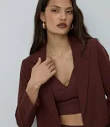 Blazer de sastrería color bordó, de corte oversized y largo, confeccionado en crepé. Presenta solapas clásicas, bolsillos frontales y detalle de pliegues en los puños.