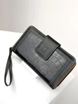 Billetera grande de cuero negro con textura de reptil y detalles de costuras en contraste. Cuenta con solapa frontal con cierre magnético y correa de muñeca extraíble.