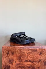Sandalias chatas de cuero negro con tiras anchas acolchadas y suela track dentada.