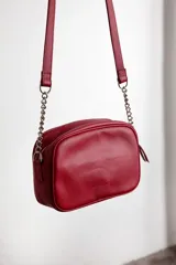 Cartera bandolera negra con diseño capitoneado en forma de V, correa de cuero y cadena plateada, cierre metálico y doble bolsillo interior.