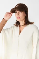 Gorro tipo baseball de tela tipo peluche color crudo, con bordado central en color marrón.