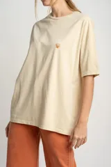 Remera color arena de algodón peinado, corte oversize y manga corta. Estampado pequeño de una concha en el pecho.