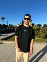 Remera negra de corte semi oversize con estampa frontal con la frase "Buena Vibra Est. 2022" en letras blancas.