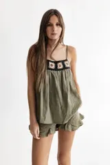 Top verde con breteles finos regulables y aplique de crochet en la pechera.