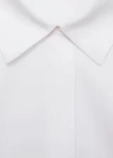 Camisa de corte recto y diseño crop, confeccionada en tejido popelín. Presenta cuello camisero clásico, cierre delantero con botones ocultos y mangas largas con puños abotonados.