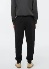 Pantalón tipo babucha de color azul oscuro, confeccionado con interior de felpa. Presenta cintura elástica con cordón de ajuste y puños acanalados en los tobillos.