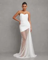 Vestido largo blanco de corte sirena con escote corazón y diseño strapless, confeccionado en tela con drapeado fruncido en el torso y falda semitransparente con cola.