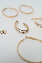 Set de siete pares de aros dorados de diversos estilos, incluyendo aros de argolla lisos, argollas texturadas, aros ovalados y aros pequeños tipo broche con diferentes formas.