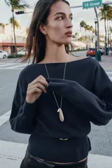 Jersey de punto color mostaza con cuello barco, manga larga con sisa ancha y detalle de cinturón fino integrado en la cintura.