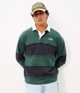 Remera tipo chomba de manga larga, con bloques de color en tonos verde y azul marino, cuello polo blanco y pequeño bordado en el pecho.