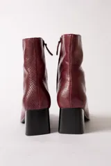 Bota de caña media con textura de reptil en color negro, punta cuadrada y taco bloque.