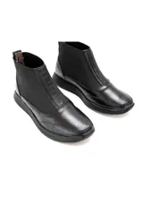 Botín tipo Chelsea de caña baja, color negro, confeccionado en cuero vacuno liso con inserciones de tejido elástico en los laterales y detalle texturizado efecto escama en el talón. Cuenta con plataforma ligera y plantilla de látex para mayor confort.