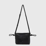 Cartera tipo bandolera de color negro, confeccionada en material texturizado con acabado mate. Presenta un diseño rectangular con detalles de nudos en los laterales y correa larga ajustable y removible. Incluye el logo de la marca grabado en letras doradas en la parte frontal.