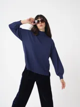 Sweater de cuello alto con mangas amplias y puños ajustados, confeccionado en tejido de punto con acabado liso.
