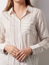 Camisa blanca a rayas verticales, marca Alex & Jordan. Tiene cuello con solapa, abertura central con botones y bolsillo aplicado en el pecho.