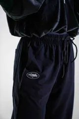 Pantalón de jogging negro de corte holgado, con cintura elástica ajustable mediante cordón y logo pequeño estampado en la pierna derecha.