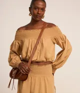 Blusa color ocre de tricolina con escote hombro a hombro con lastex, mangas largas con lastex en los puños y regulador en la parte baja.