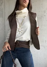 Chaleco de gamuza color chocolate con costuras decorativas en los bordes. Diseño sin mangas, abierto al frente, con una textura suave y acabado mate.