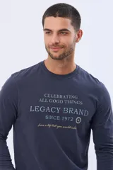 Remera de algodón de manga larga color azul marino, con cuello redondo y estampado frontal en tonos celestes y dorados que dice "Celebrating All Good Things Legacy Brand Since 1972" y "Live a life that you would relive".