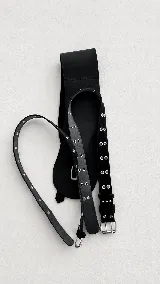 Cinto de cuero con hebilla cuadrada metálica y doble hilera de ojales decorativos.