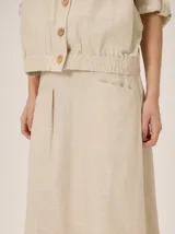 Falda midi color bordó con brillo sutil y detalle de lazo en la cintura.