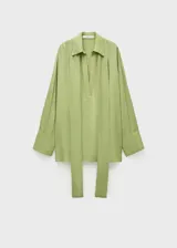 Camisa de gasa color verde oliva, de corte oversize y diseño recto. Presenta cuello camisero con escote en V profundo, mangas largas con puños y bajo con aberturas laterales.