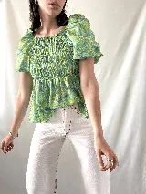Blusa verde con estampado floral en tonos celeste y marrón, escote cuadrado con elástico, mangas cortas abullonadas y cuerpo fruncido.