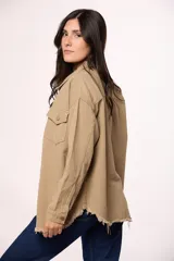 Sobrecamisa de jean color marrón, con cierre frontal de botones metálicos, bolsillos frontales con solapa y ruedo deshilachado.