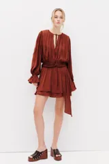 Vestido corto marrón de tejido drapeado con cuello redondo, manga larga abullonada y detalle de nudo en la cintura con tiras colgantes.