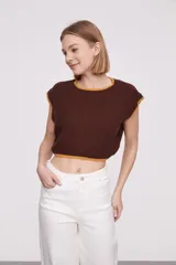 Chaleco corto de punto color marrón con ribete amarillo en cuello, sisas y bajo.