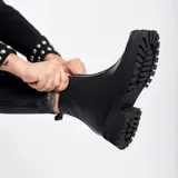 Bota corta de cuero vacuno color negro, con suela de goma tipo track y punta cuadrada. Presenta un detalle central de cuero con textura de reptil y cierre lateral interno.