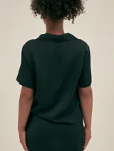 Camisa verde claro de manga corta con cuello camisero y botones.