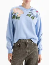 Buzo de corte oversize color marrón chocolate, con cuello redondo y diseño estampado de flores en la parte frontal. Presenta mangas largas con puños ajustados.