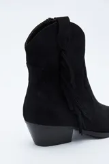 Bota texana de gamuza negra con caña baja, flecos laterales decorativos, costuras estilo western y taco bajo inclinado.