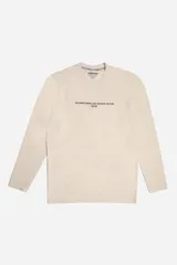Remera de manga larga en color beige con textura acanalada sutil. Presenta una estampa frontal con texto en color gris oscuro y un ajuste regular cómodo.