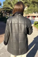 Campera de cuero color tostado con diseño de paneles, cuello alto y puños con forro de corderito sintético. Presenta cierre frontal con botones grandes y bolsillos laterales.