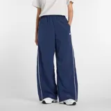 Pantalón deportivo de corte holgado y tiro medio, confeccionado en tejido ripstop de nailon. Presenta un diseño en color azul marino con ribetes laterales en contraste blanco y logo de la marca bordado en la parte superior. Cuenta con cintura elástica y bolsillos laterales.