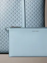 Cartera tote pequeña y estructurada de Calvin Klein en color celeste, con estampado integral de monograma CK. Incluye asas de mano dobles y una cartera mini interior a juego con cierre superior.