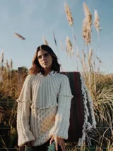Sweater de lana merino color marfil, tejido a mano con puntos combinados de trenzas, bodoques y punto panal, de mangas largas y silueta relajada.