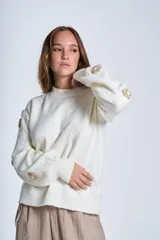 Sweater color crema de hilado frizado con cuello redondo y apliques de flores color beige en las mangas.