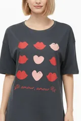 Remera marrón de manga corta con cuello redondo y diseño holgado. En el frente presenta una estampa en tono verde claro con forma de corazón, estrellas y la frase 'You are my lucky'.