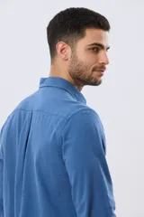 Camisa de lino de manga larga en color beige, con cuello camisero, cierre frontal de botones y un bolsillo ojal en el pecho.