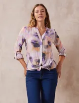 Blusa estampada de Zac & Rachel con cuello a la base, escote en V y botones. Tiene un bolsillo aplicado en la parte delantera, mangas largas regulables con presilla y botón, y terminación anudada opcional.