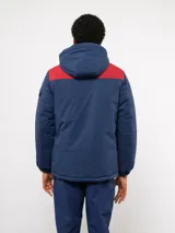 Parka de abrigo Umbro del Club Nacional de Football, con diseño de bloques de color en azul, rojo y blanco. Cuenta con capucha, cierre frontal, bolsillos frontales y el escudo del club bordado en el pecho.